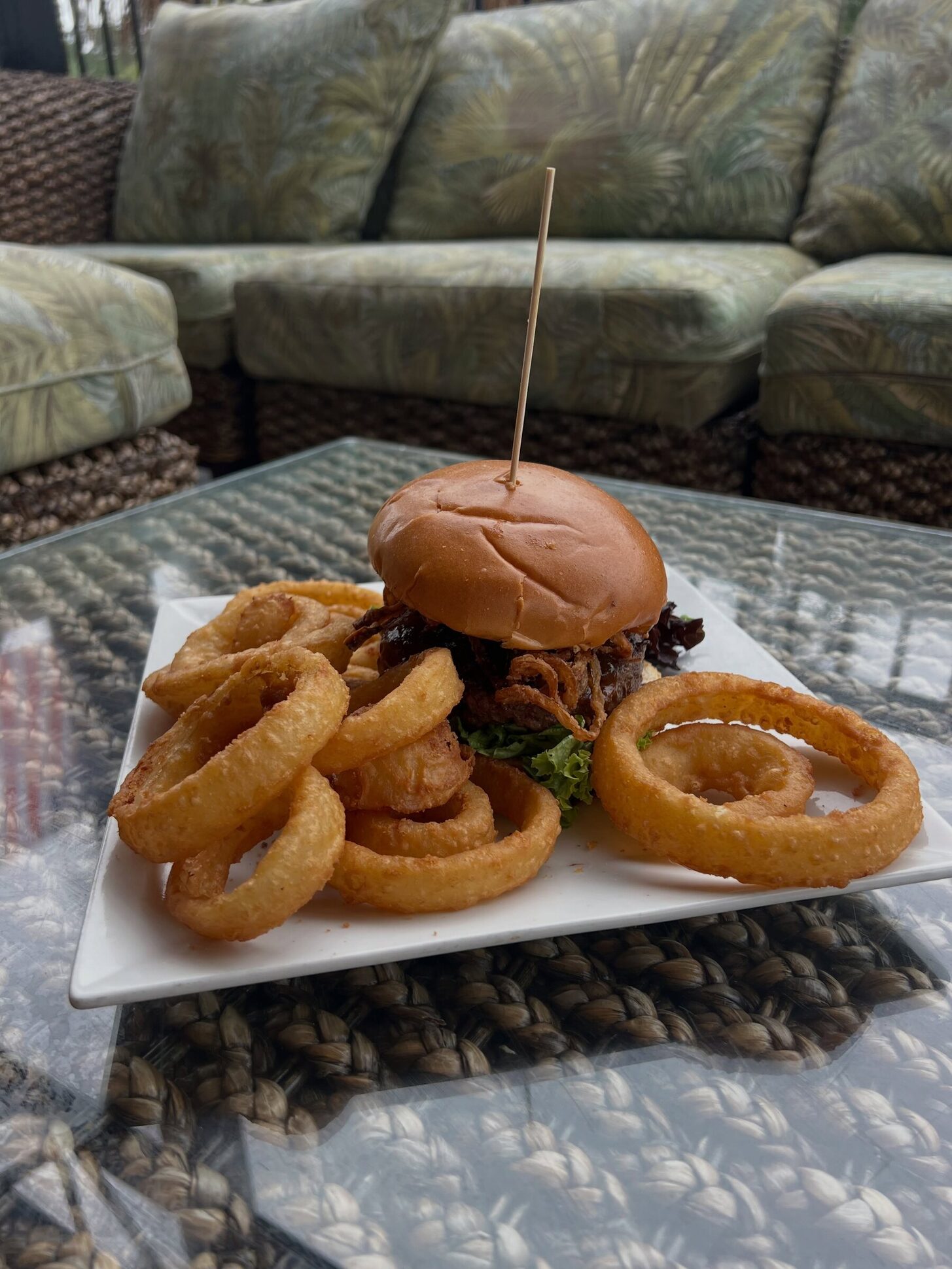 A burger with onion rings on a patio table
