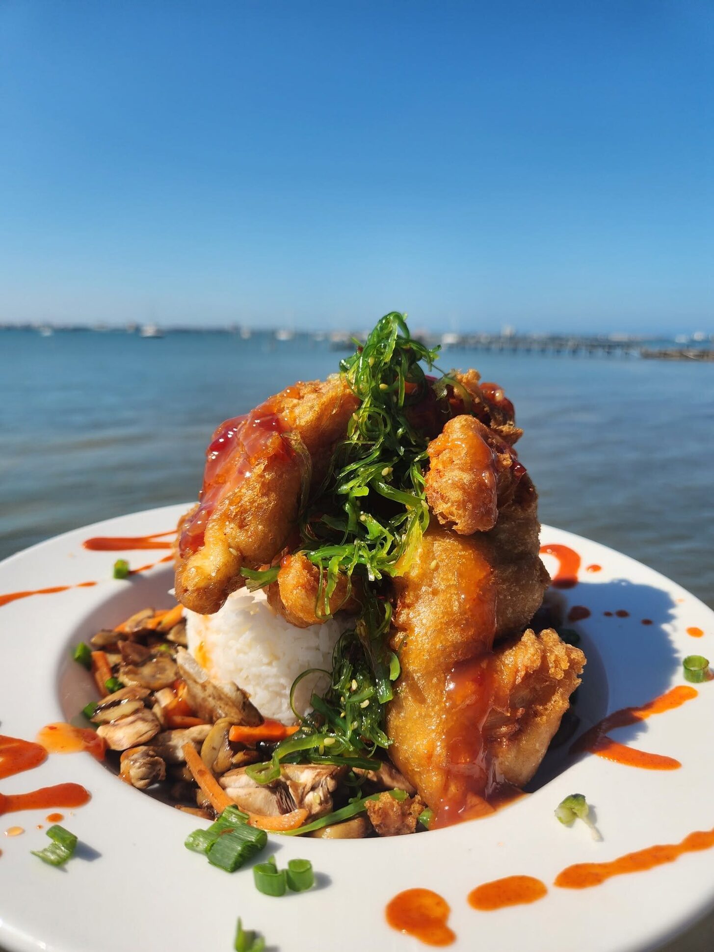 A fried seafood plate on the O'Maddy's rail against the open bay