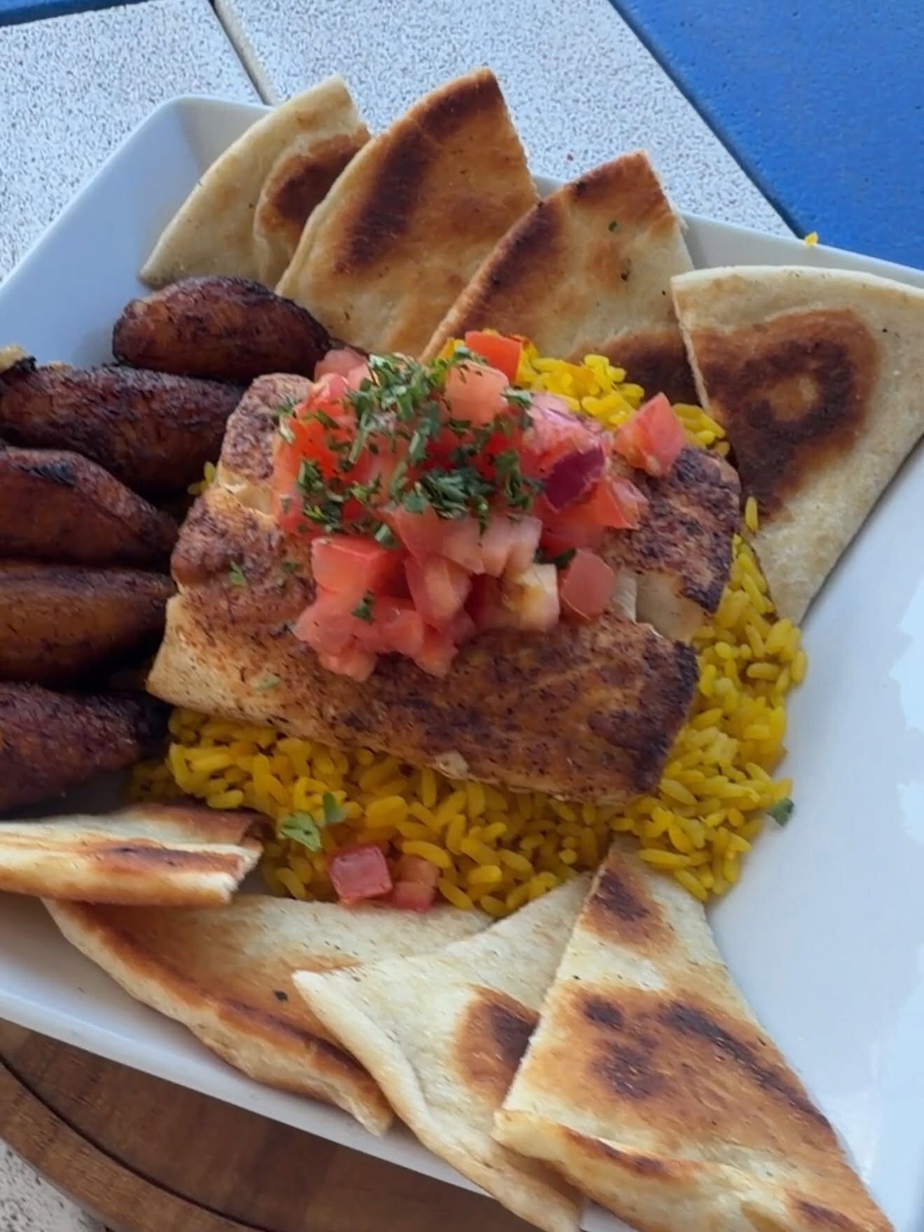 Grilled fish over yellow rice with pita