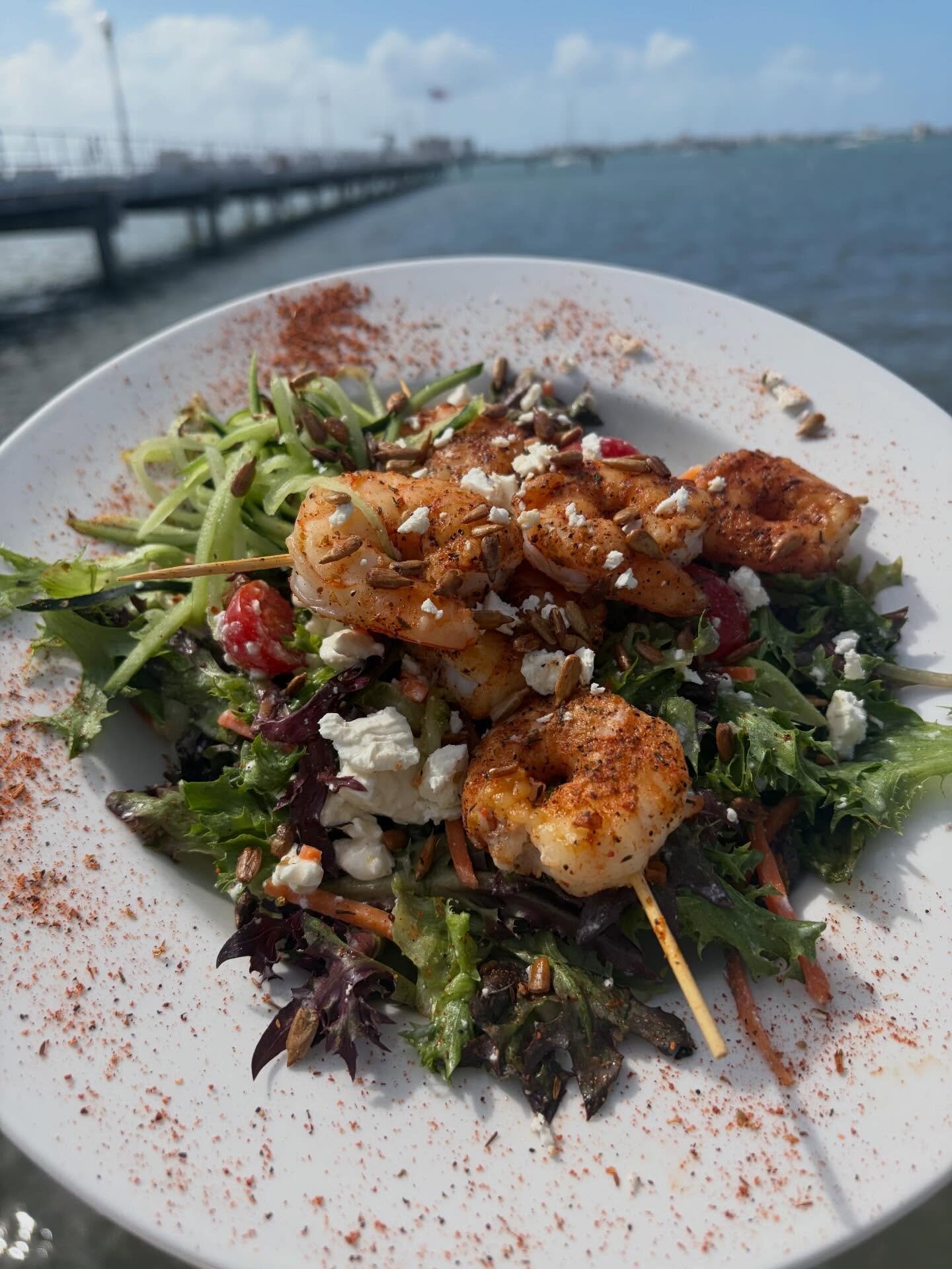 A blackened shrimp salad with the pier behind