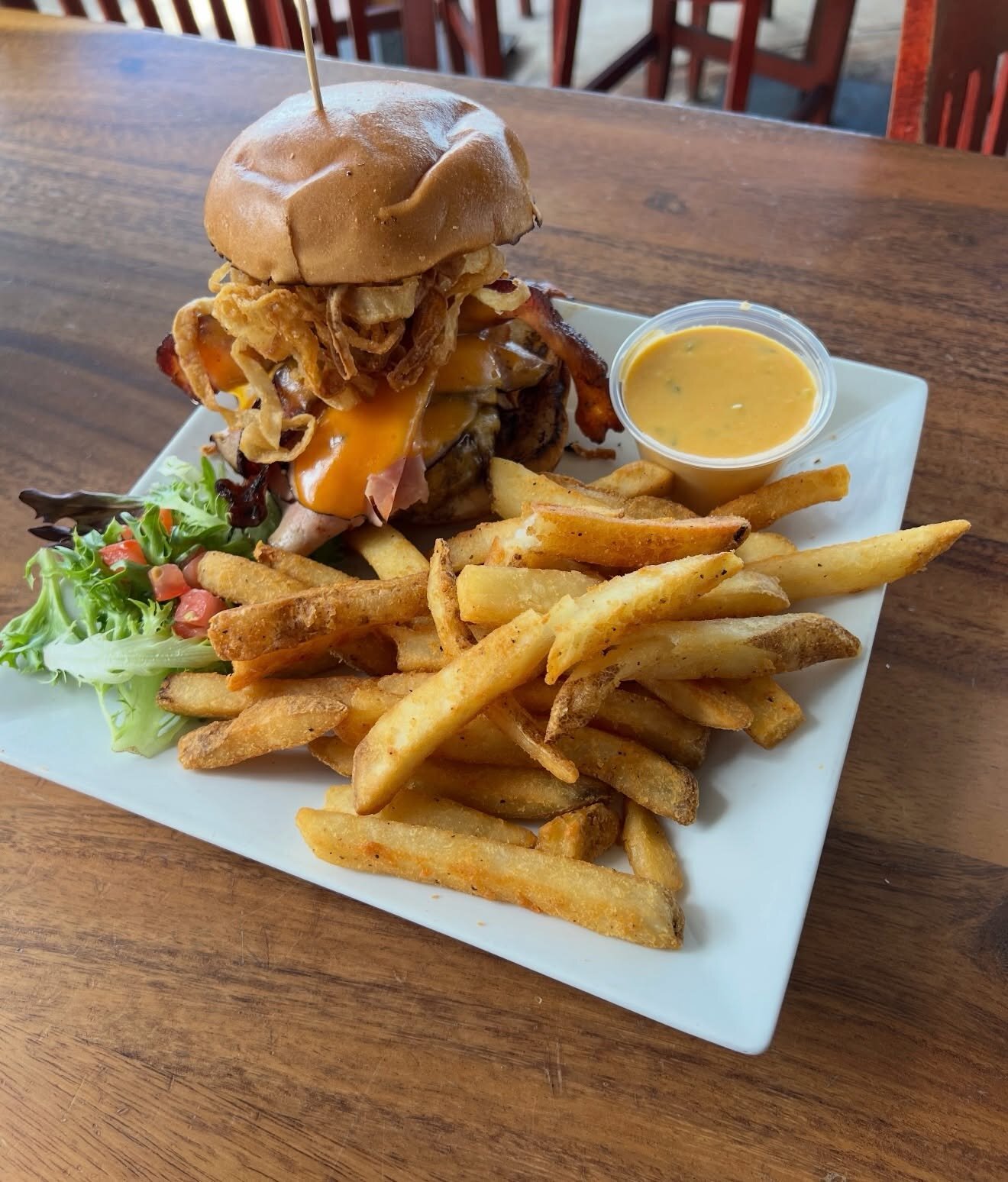 A tall burger with onion straws and fries