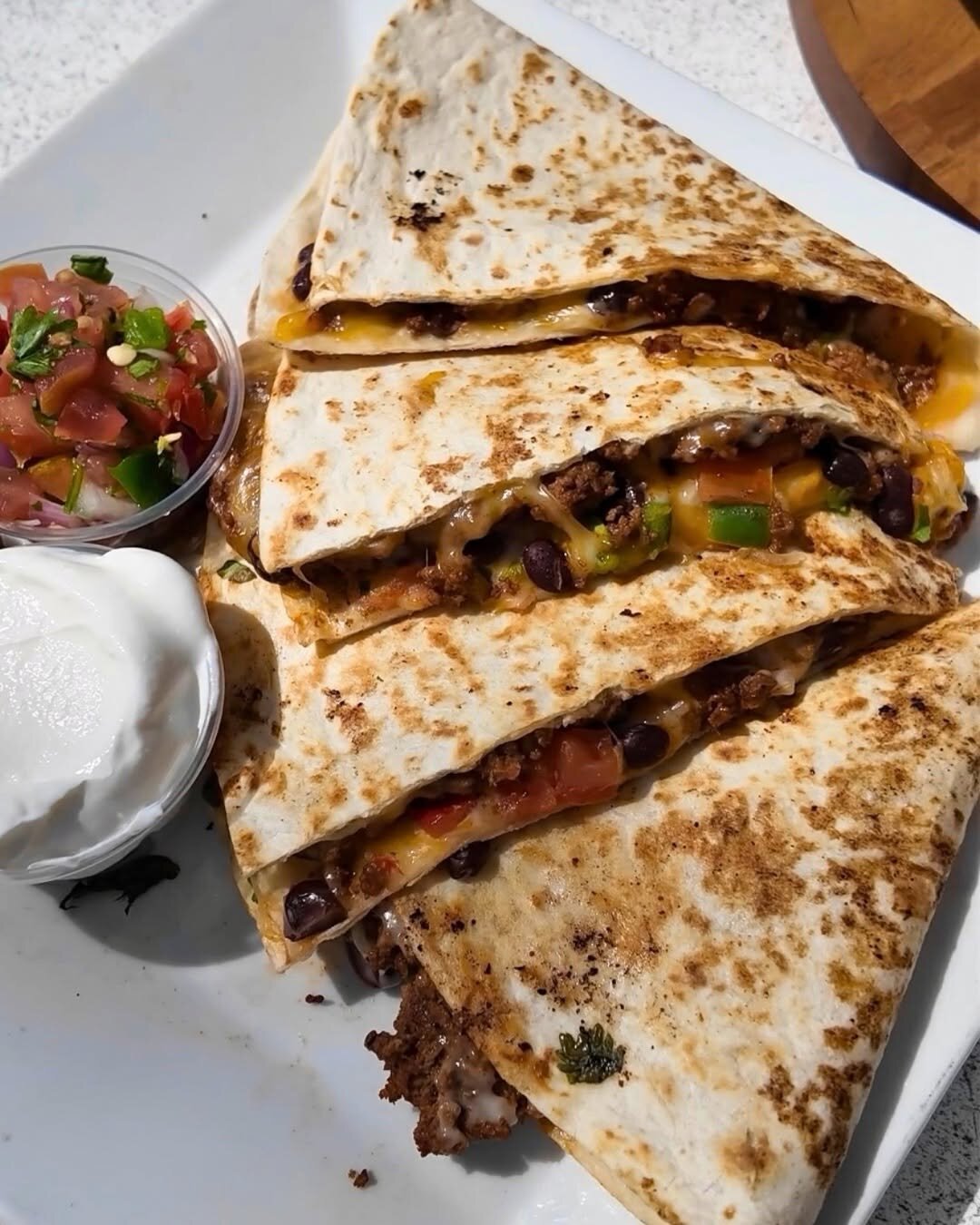 A quesadilla with pico de gallo and sour cream