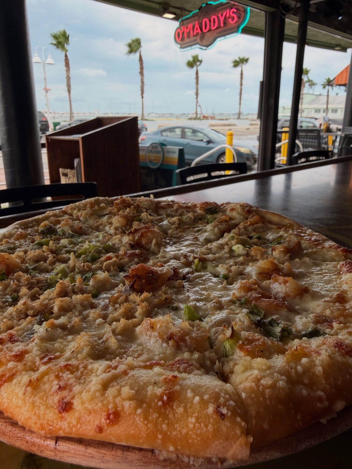 A pizza on the bar under the O'Maddy's neon sign