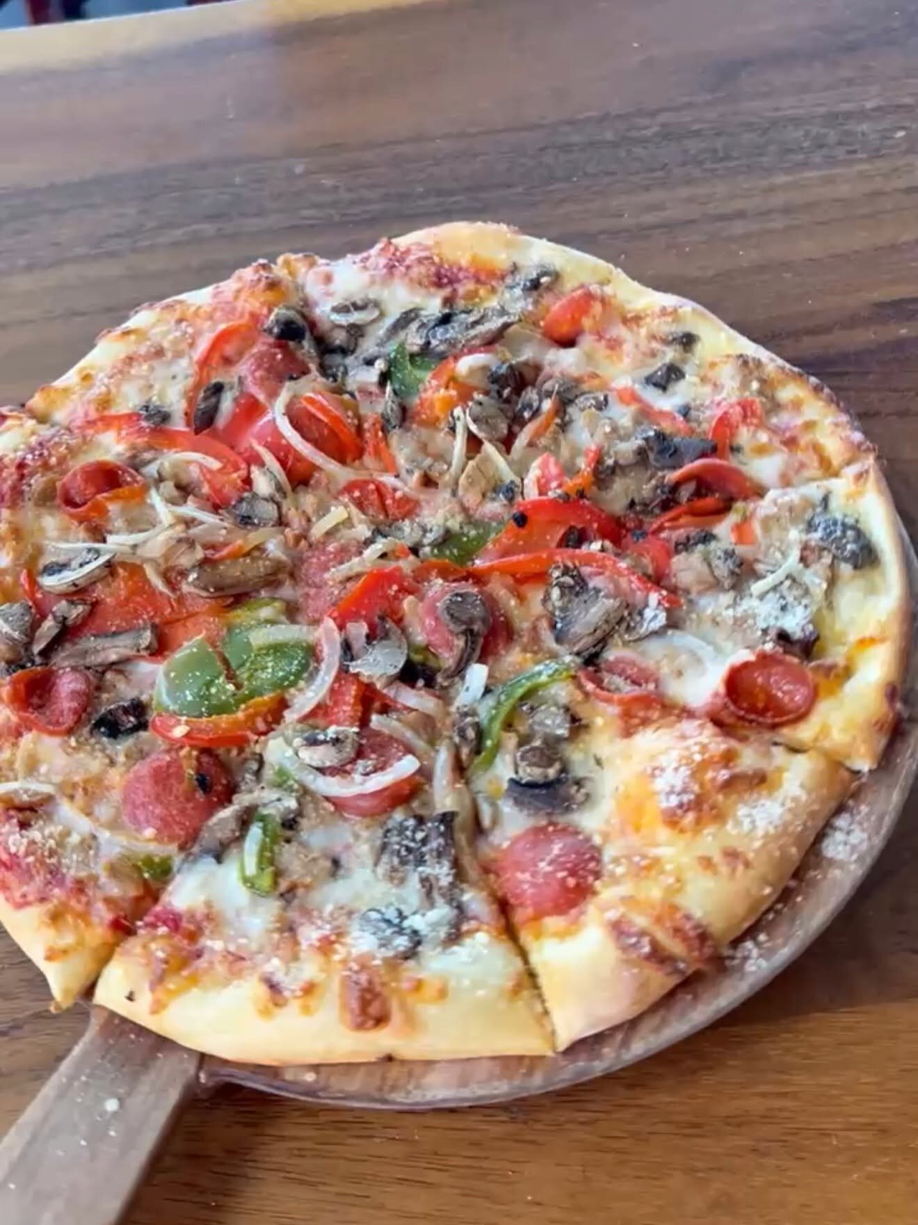 A supreme pizza on a wood board