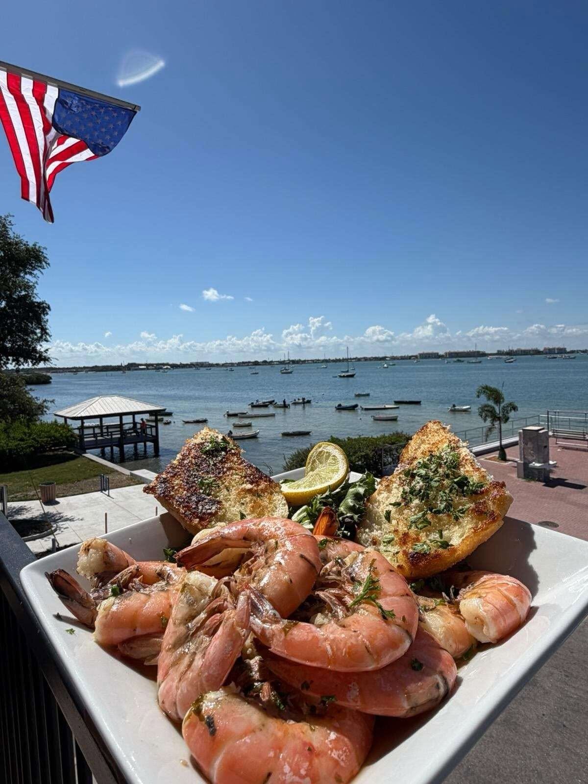 Peel-and-eat shrimp on the O'Maddy's upper deck, with the flag and the bay behind