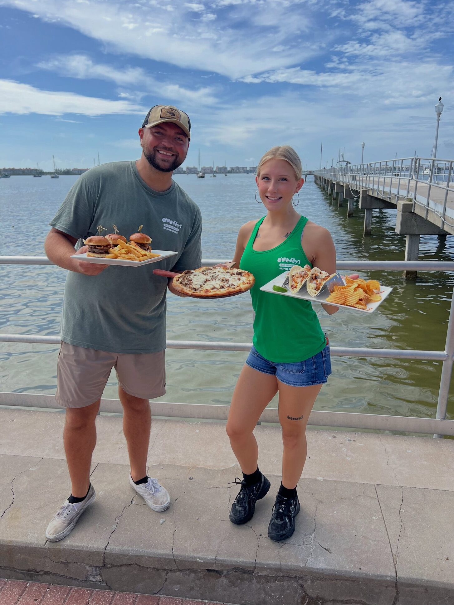 Two O'Maddy's crew members holding plates on the Gulfport pier