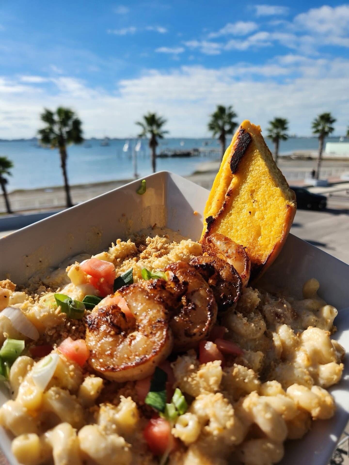 Blackened shrimp mac with palms and the bay behind, on the O'Maddy's rail